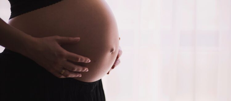 closeup of woman holding her pregnant belly