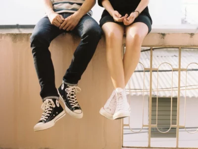 a couple wearing sneakers sitting ontop of a roof top