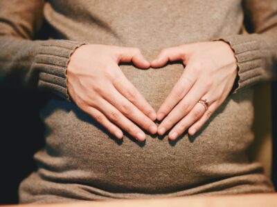 Pregnant woman with hands held in heart shape