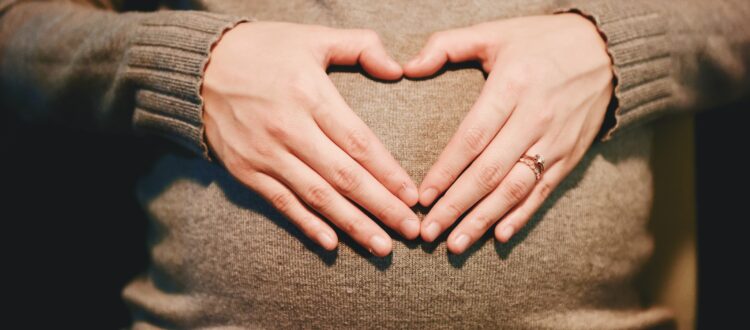 Pregnant woman with hands held in heart shape